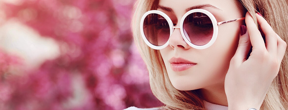 Junge Dame mit Sonnenbrille vor rosa Hintergrund